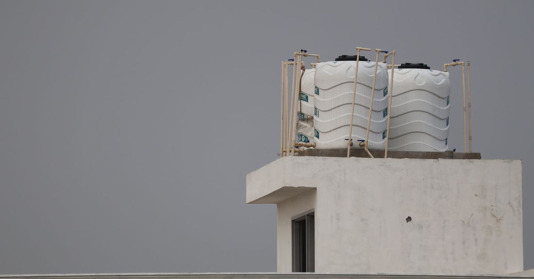 White water tanks on a rooftop with architectural design, under a gray sky.