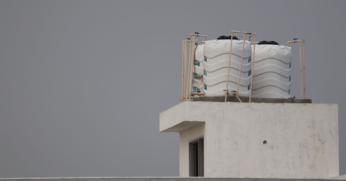 White water tanks on a rooftop with architectural design, under a gray sky.
